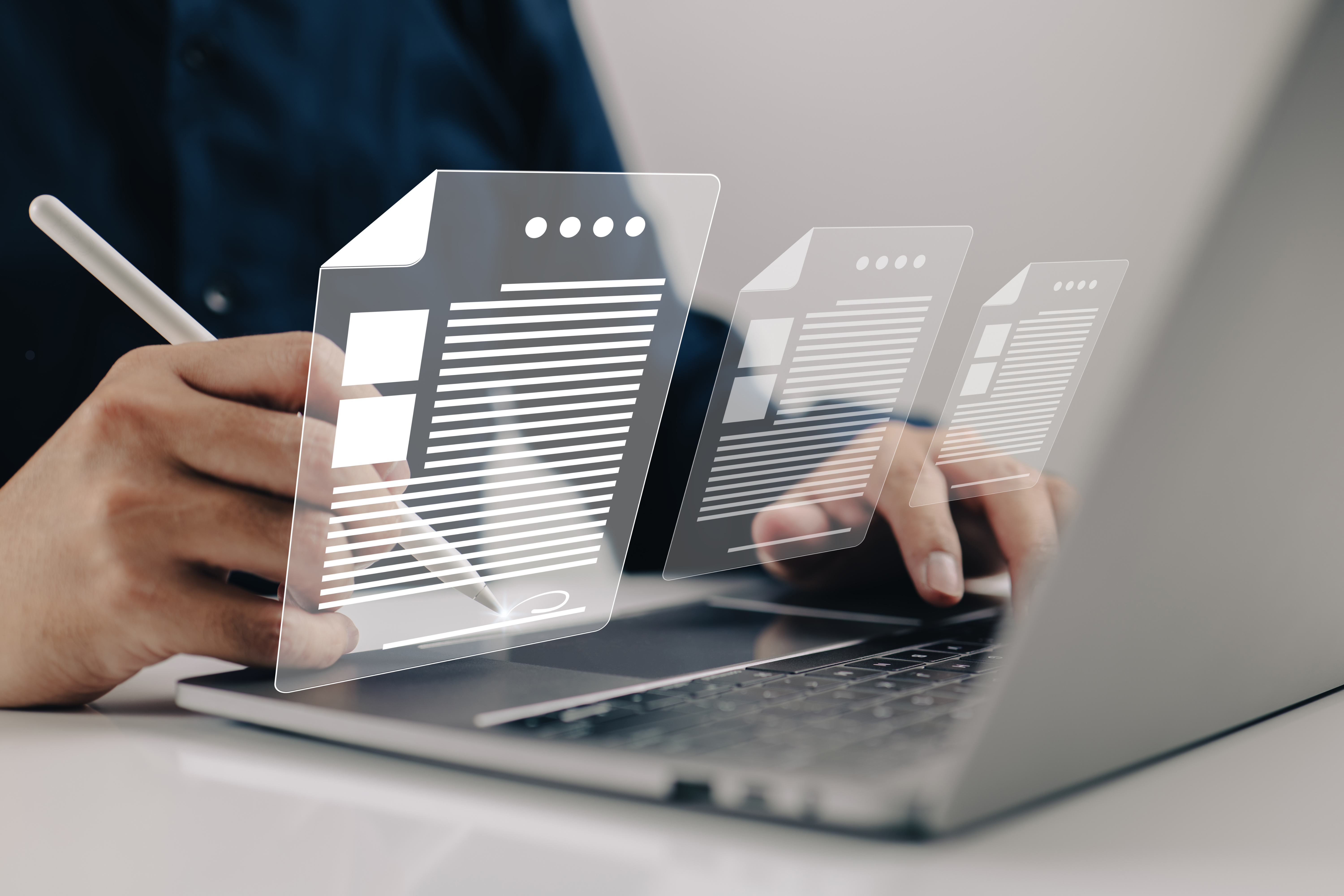 Klawiatura laptopa, nad którą wyświetlają się interaktywne grafiki symbolizujące dokumenty.1